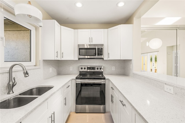 kitchen featuring white cabinetry, appliances with stainless steel finishes, sink, and light stone counters