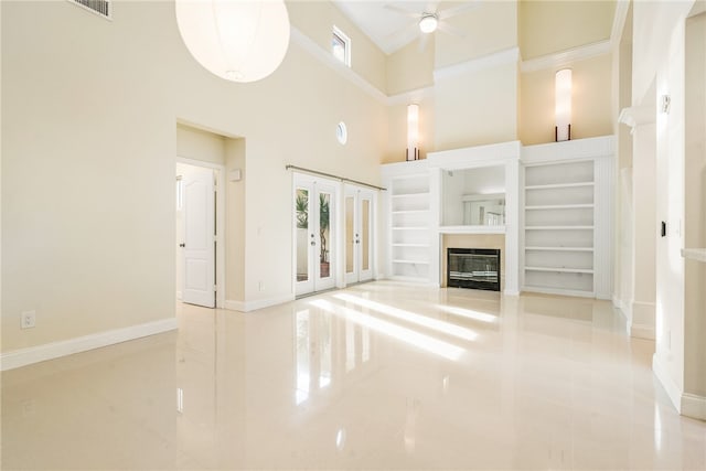 unfurnished living room featuring french doors, a towering ceiling, ornamental molding, light tile patterned flooring, and ceiling fan