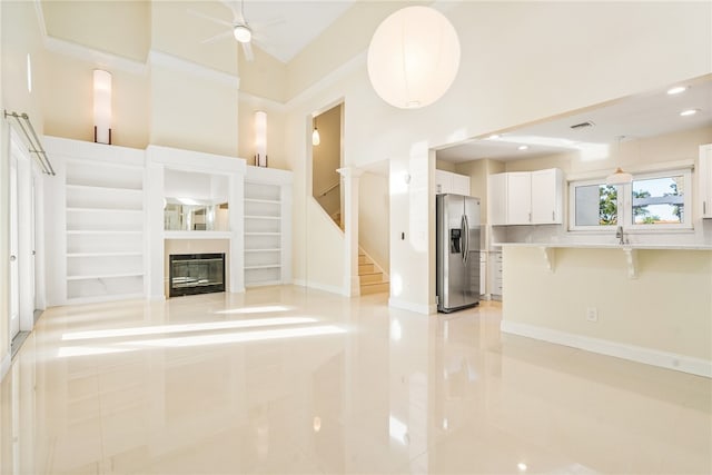 unfurnished living room featuring light tile patterned floors, crown molding, and ceiling fan