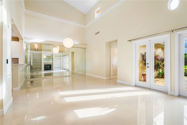 unfurnished living room with french doors, high vaulted ceiling, and light tile patterned floors