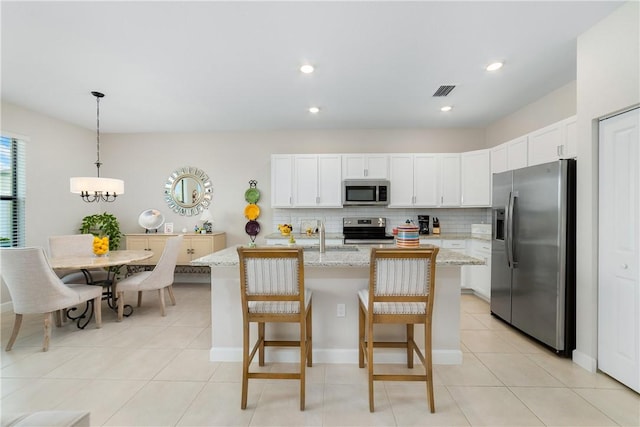 10134 W Villa Cir, Vero Beach, FL 32966 - kitchen featuring stainless steel appliances, white cabinetry, decorative backsplash, an island with sink, and recessed lighting
