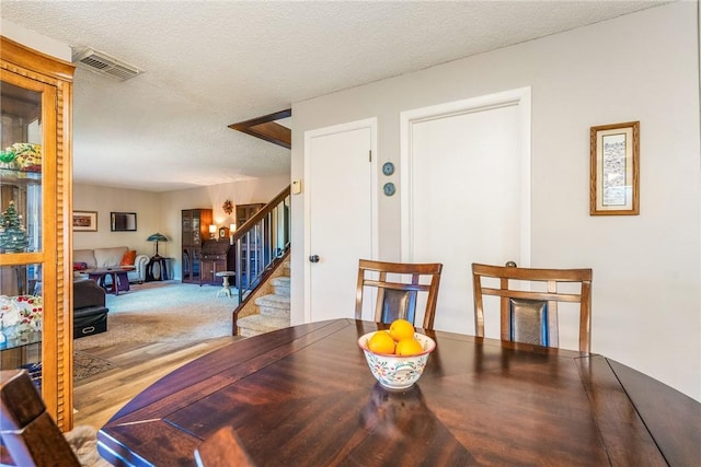 dining room with stairway, visible vents, a textured ceiling, and wood finished floors