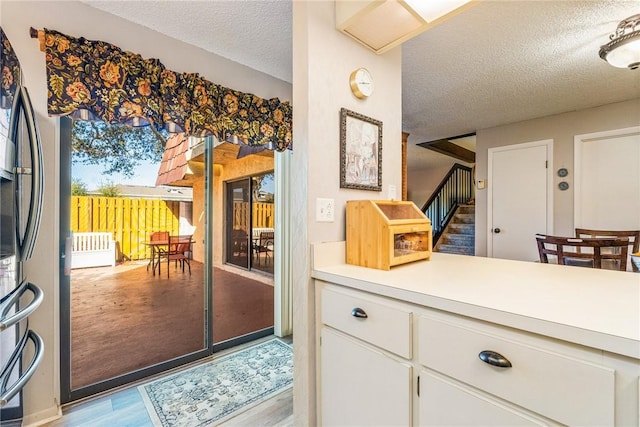 1170 6th Ave Unit 10A, Vero Beach, FL 32960 - kitchen with a textured ceiling, freestanding refrigerator, wood finished floors, white cabinetry, and light countertops