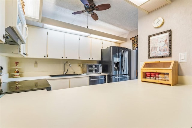 kitchen featuring a textured ceiling, a sink, white cabinets, light countertops, and appliances with stainless steel finishes