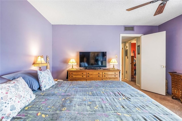 bedroom featuring light carpet, a ceiling fan, visible vents, and a textured ceiling