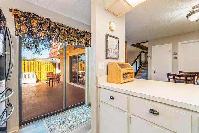 entryway with light wood-style flooring, stairway, and a textured ceiling