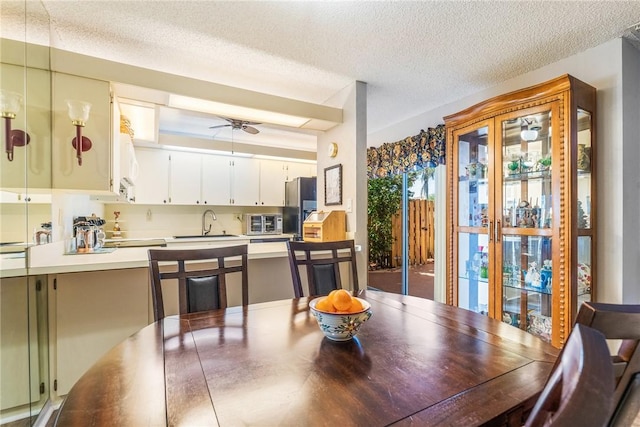 kitchen featuring white cabinets, a ceiling fan, light countertops, stainless steel refrigerator with ice dispenser, and a sink