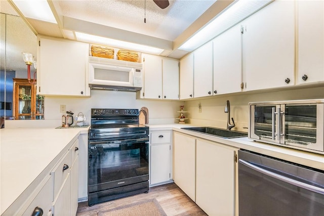 kitchen with white microwave, light countertops, black electric range, stainless steel dishwasher, and a sink