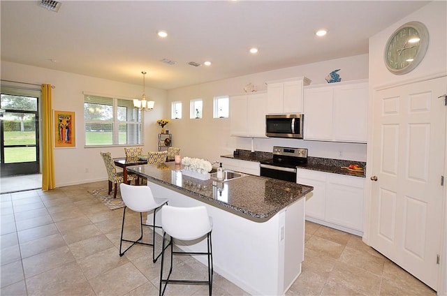 kitchen with white cabinets, stainless steel appliances, and a kitchen island with sink