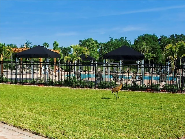 view of playground with a community pool and a lawn