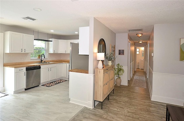 726 41st Ave, Vero Beach, FL 32968 - kitchen with dishwasher, a sink, white cabinets, light wood-type flooring, and a textured ceiling