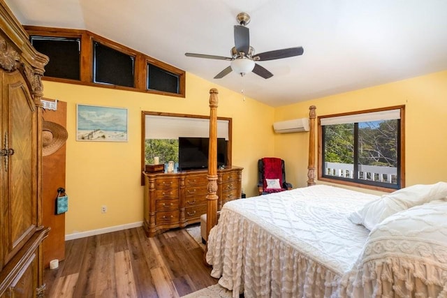 bedroom with lofted ceiling, wood finished floors, an AC wall unit, baseboards, and a ceiling fan