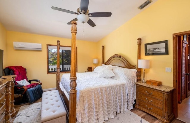 bedroom with a wall mounted air conditioner, wood finished floors, ceiling fan, and baseboards