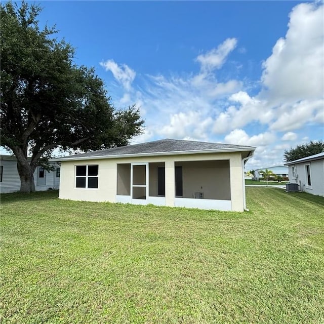 rear view of house featuring stucco siding, a yard, and central AC unit