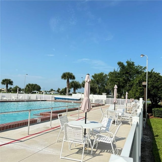 view of patio / terrace with outdoor dining area, a community pool, and fence