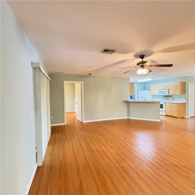 unfurnished living room featuring ceiling fan, visible vents, baseboards, and light wood-style flooring