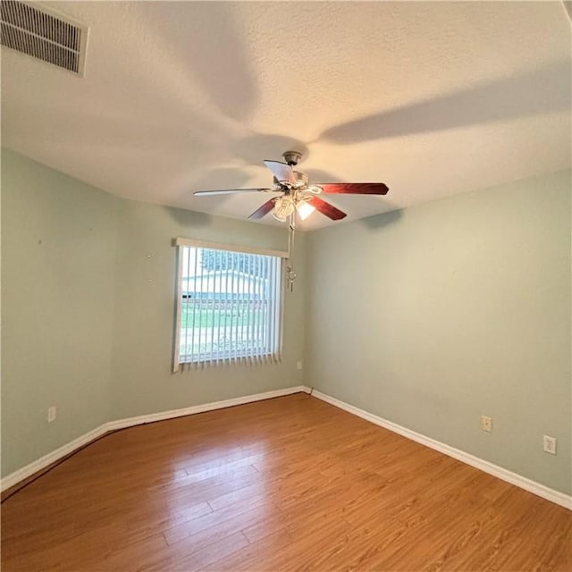 spare room featuring visible vents, baseboards, ceiling fan, and wood finished floors