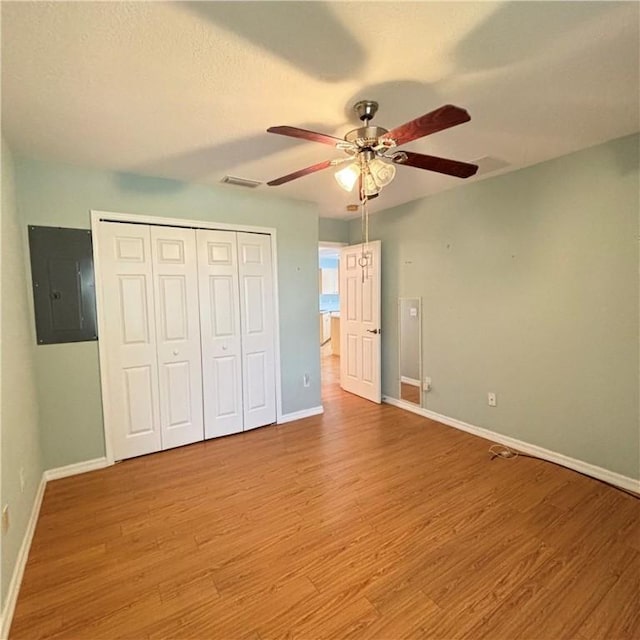 unfurnished bedroom with visible vents, baseboards, electric panel, wood finished floors, and a closet