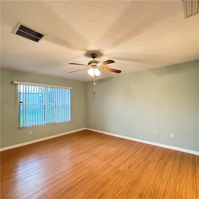 spare room with baseboards, light wood-style floors, visible vents, and ceiling fan