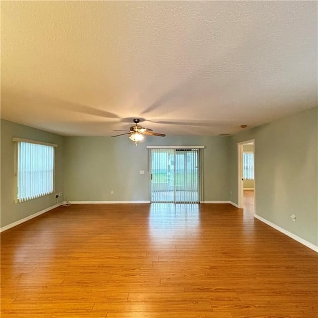 unfurnished room with light wood finished floors, baseboards, a textured ceiling, and a ceiling fan