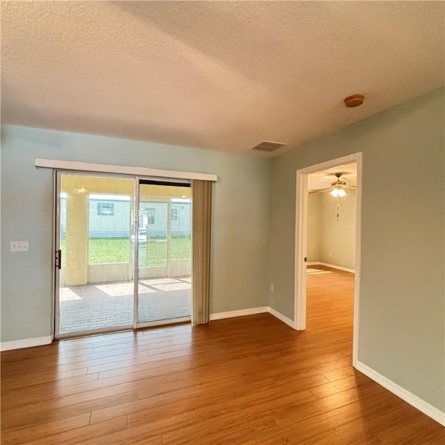 spare room featuring hardwood / wood-style floors, baseboards, visible vents, and a textured ceiling