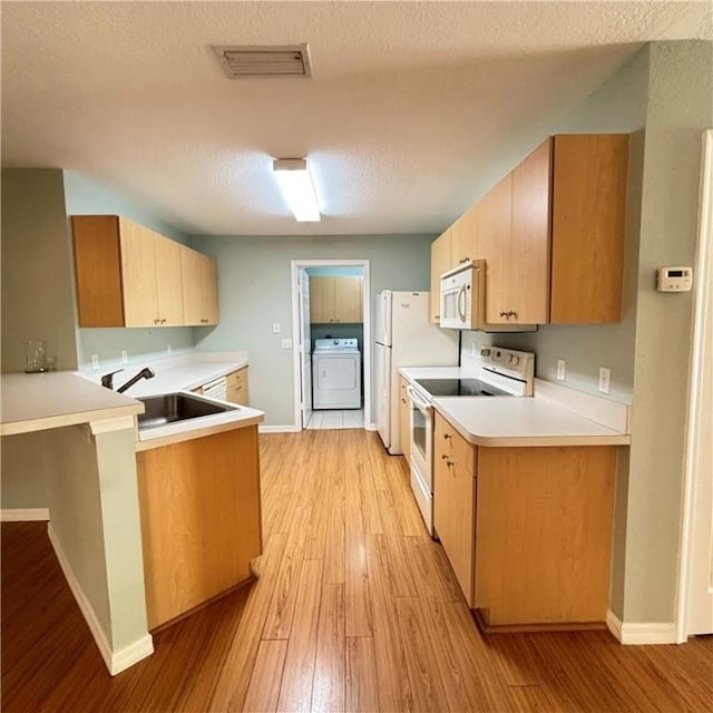 kitchen with white appliances, washer / dryer, light wood-style flooring, a sink, and light countertops