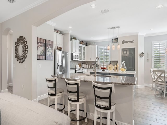 kitchen with sink, appliances with stainless steel finishes, hanging light fixtures, white cabinets, and decorative backsplash