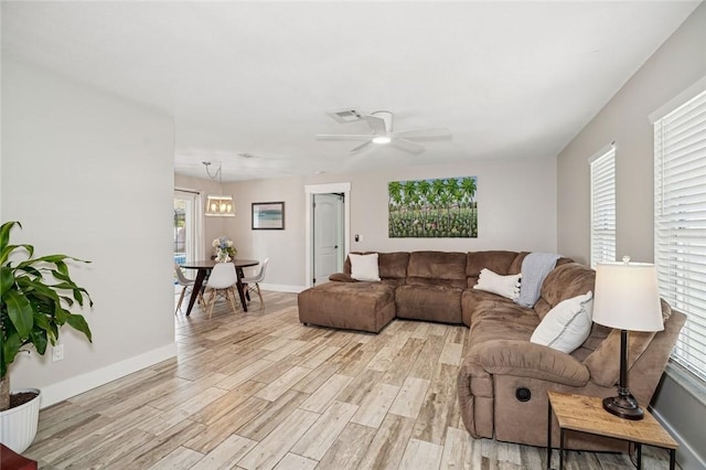 living room featuring light wood finished floors, a wealth of natural light, a ceiling fan, and visible vents