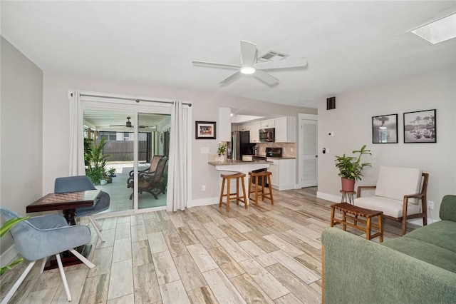 living area with a ceiling fan, baseboards, light wood finished floors, and visible vents