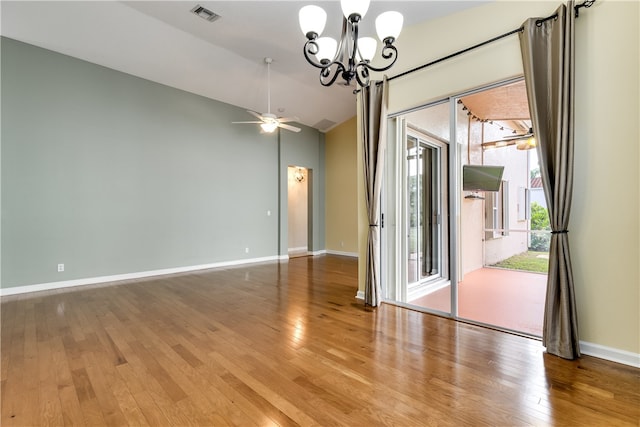 empty room featuring hardwood / wood-style floors, ceiling fan with notable chandelier, and lofted ceiling