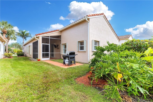 rear view of property featuring a lawn, a sunroom, and a patio