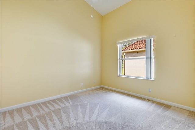 carpeted empty room with lofted ceiling