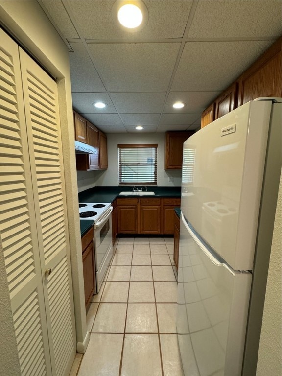 kitchen featuring light tile patterned floors, a drop ceiling, sink, and white appliances