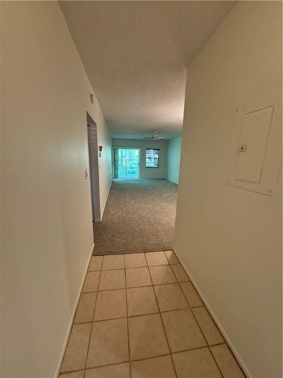 hall with light carpet, a textured ceiling, and electric panel