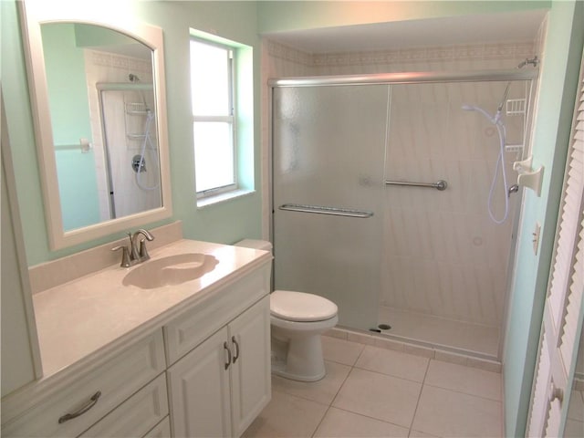 bathroom with toilet, vanity, a shower with door, and tile patterned floors