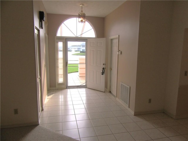 entryway with an inviting chandelier and light tile patterned floors