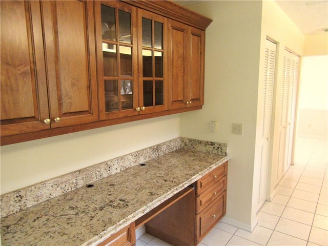 kitchen with light tile patterned floors, built in desk, and light stone counters