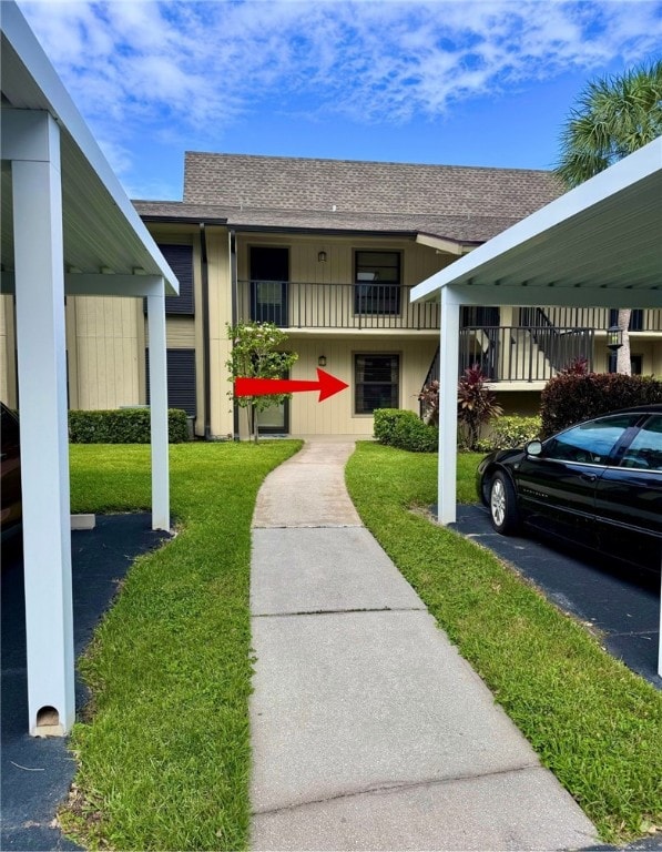 exterior space featuring a front lawn, a balcony, and a carport