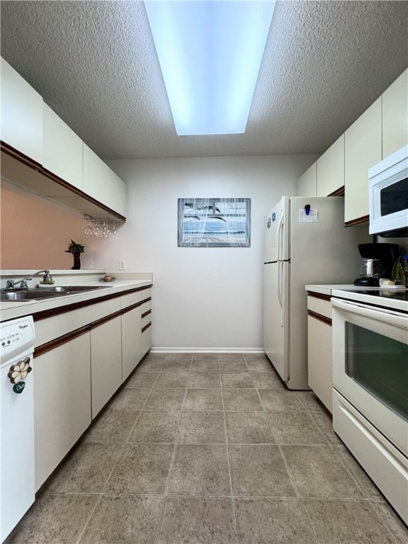 kitchen with white appliances, white cabinetry, sink, and a textured ceiling