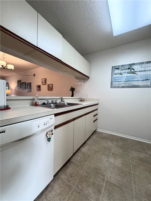 kitchen featuring white dishwasher, white cabinetry, sink, and a textured ceiling