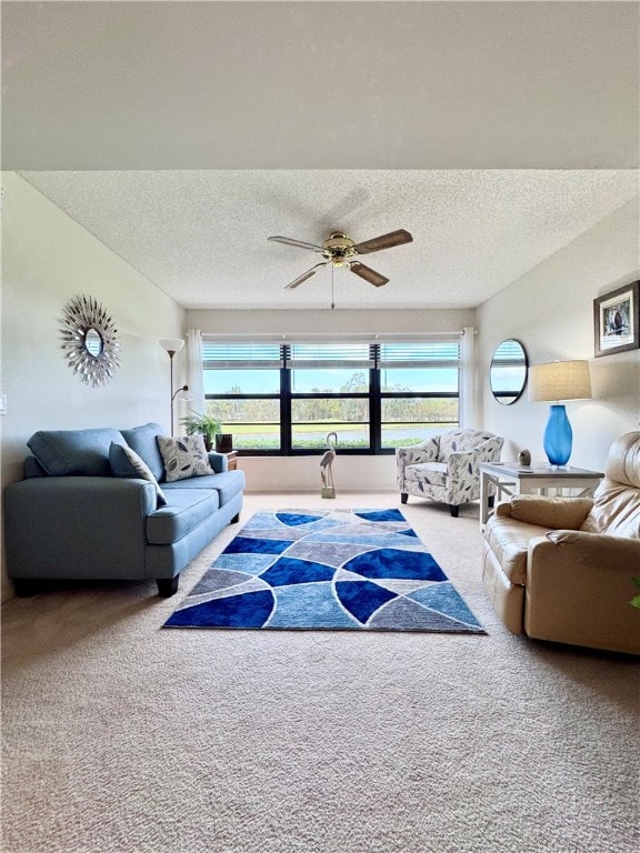 carpeted living room with ceiling fan, plenty of natural light, and a textured ceiling