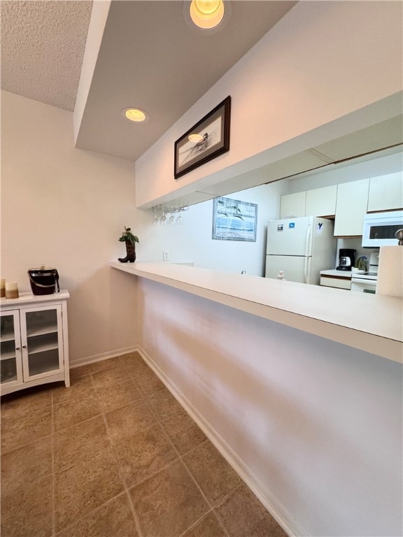 kitchen with white cabinetry, white appliances, and tile patterned floors