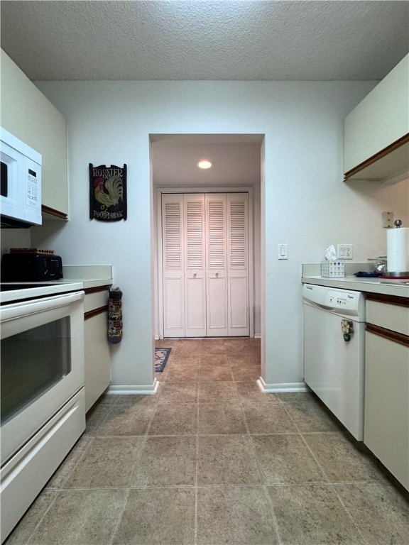 kitchen with white appliances, a textured ceiling, and white cabinets