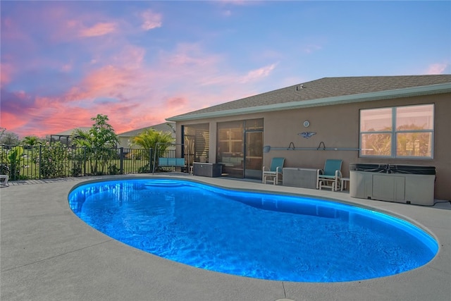 pool at dusk with a patio area