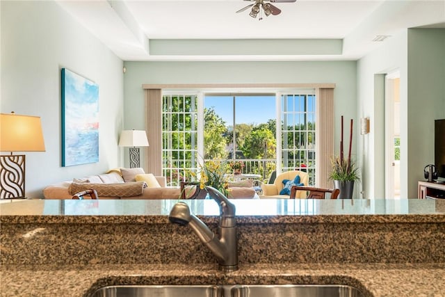 kitchen featuring ceiling fan, dark stone countertops, visible vents, and a sink