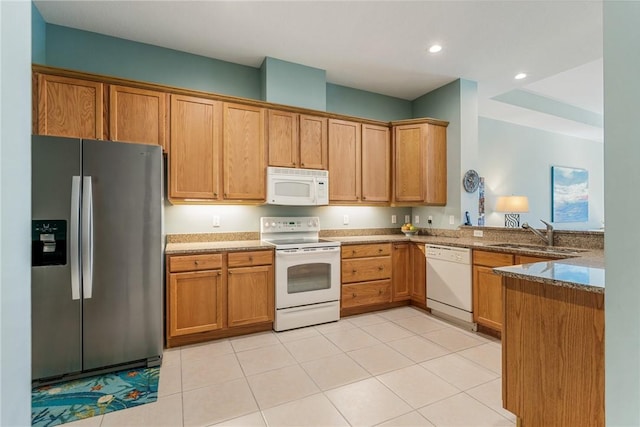 kitchen with white appliances, a peninsula, recessed lighting, stone countertops, and a sink