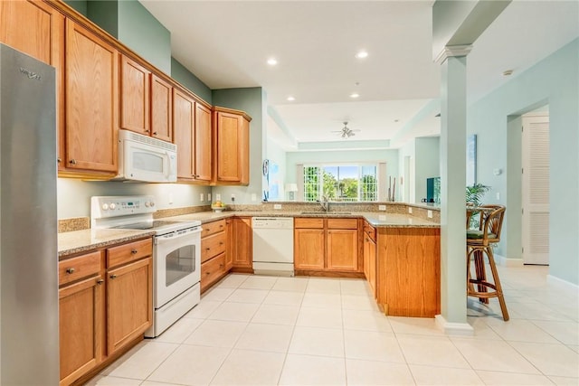 kitchen featuring white appliances, light stone counters, a peninsula, recessed lighting, and a sink