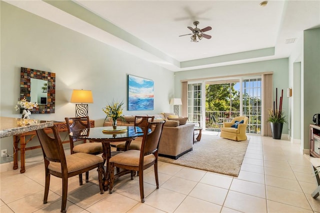 dining room with light tile patterned floors, baseboards, visible vents, a tray ceiling, and ceiling fan