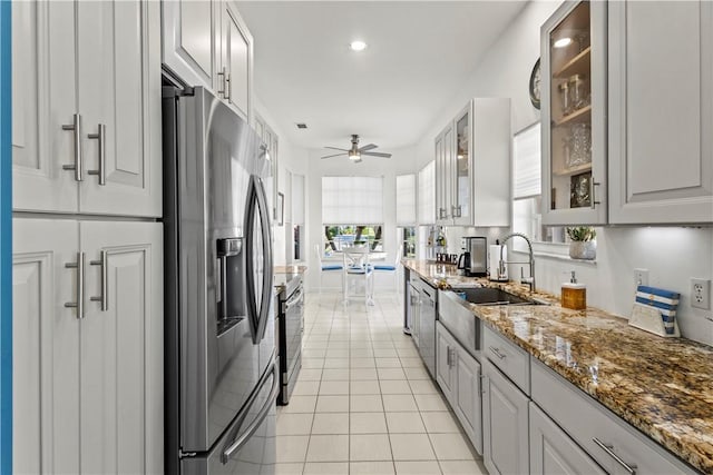 kitchen with sink, light stone counters, light tile patterned floors, appliances with stainless steel finishes, and ceiling fan