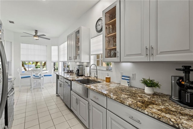 kitchen with gray cabinetry, sink, stainless steel dishwasher, and light tile patterned floors